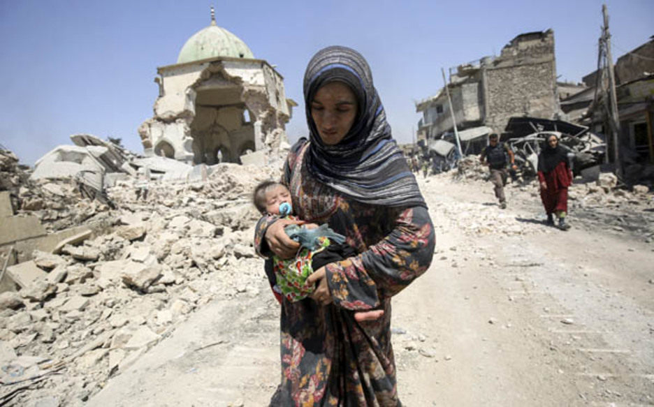 Una mujer y su hijo pasan junto a los restos de la mezquita Al-Nuri, en Mosul, ciudad que ha sido la capital del Estado Islámico durante los tres últimos años. (Ahmad AL-RUBAYE)