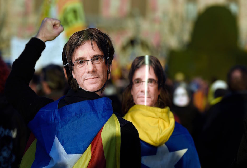 Manifestantes con caretas de Puigdemont. (Lluis GENÉ / AFP)