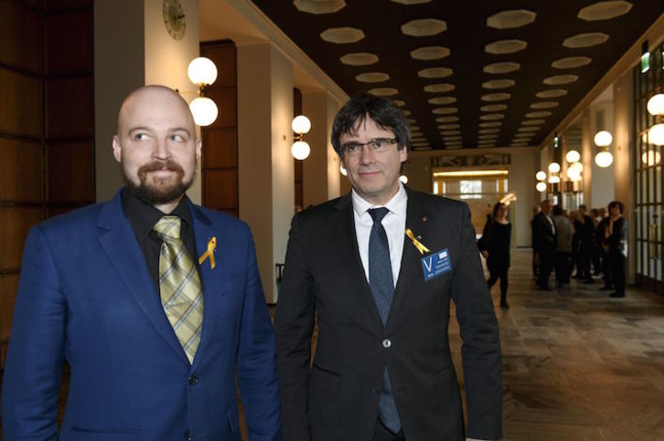 Puigdemont, junto a un parlamentario finlandés durante su visita a la Cámara del país. (Martti KAINULAINEN/AFP)