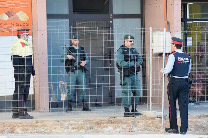 Dos guardias civiles y un mosso, ante el edificio de Viladecans donde se ha practicado una de las detenciones. (Josep LAGO/AFP)
