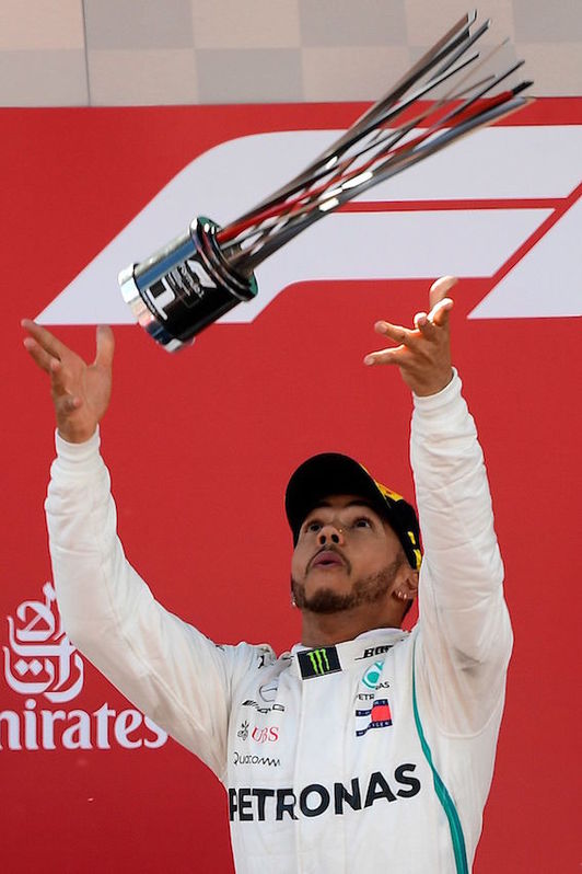 Hamilton lanza el trofeo al aire. (Lluis GENE/AFP)