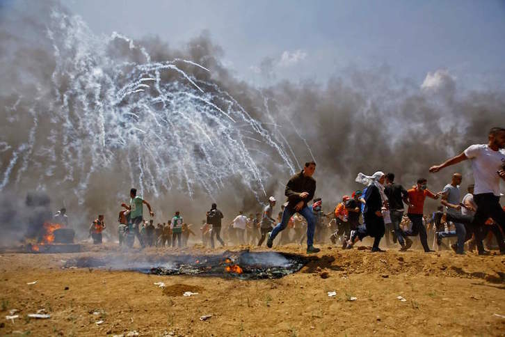 Palestinos huyen de los gases y los disparos israelíes. (MOHAMMED ABED / AFP)