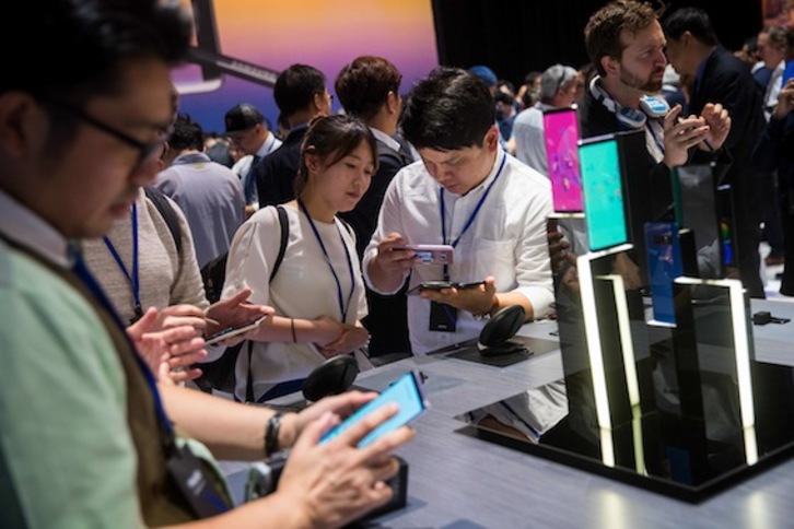 Varias personas examinan dispositivos Samsung durante un evento en Nueva York. (Drew ANGERER/AFP)