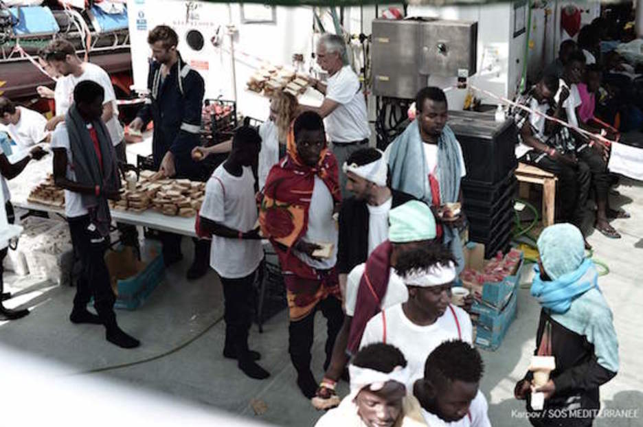 Los migrantes a bordo del ‘Aquarius’ recogen alimentos. (AFP)