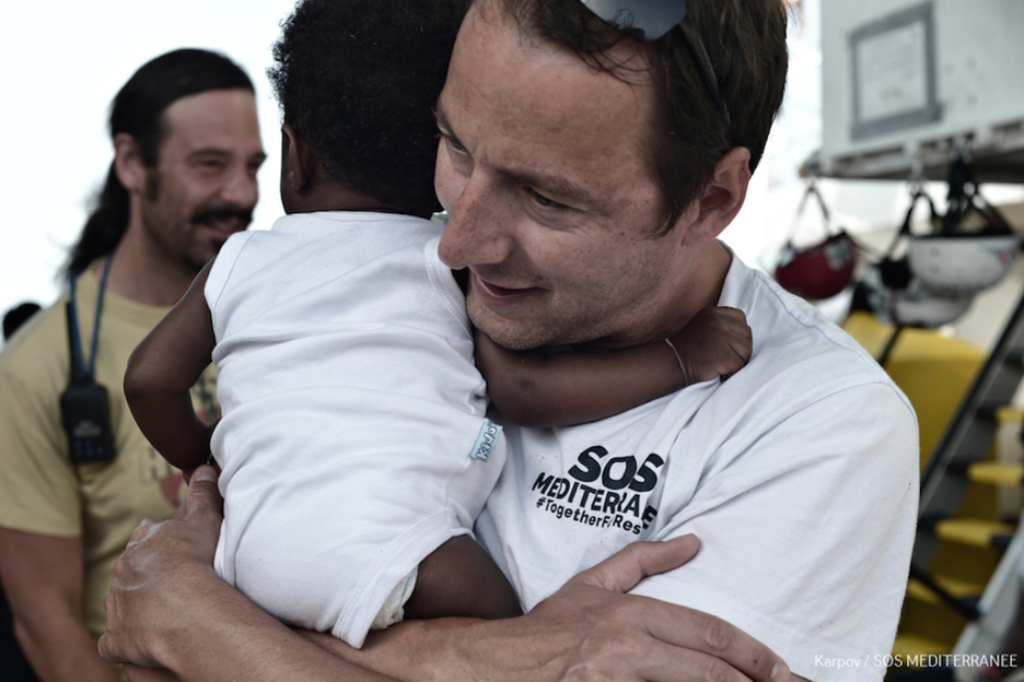 Uno de los tripulantes abraza a un bebé. (Kenny KARPOV | SOS MEDITERRANEE)