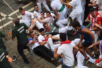 Un grupo de corredores rueda por el suelo tras el paso de los Fuente Ymbro por Estafeta. (Jon URBE/FOKU)