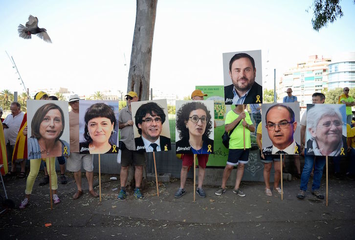 Un grupo de personas con retratos de Puigdemont y algunos de los presos y exiliados catalanes. (Josep LAGO/AFP)