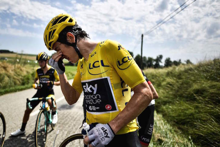 El maillot amarillo, Geraint Thomas, se limpia los ojos tras verse afectado por el gas lacrimógeno. (Marco BERTORELLO/AFP)