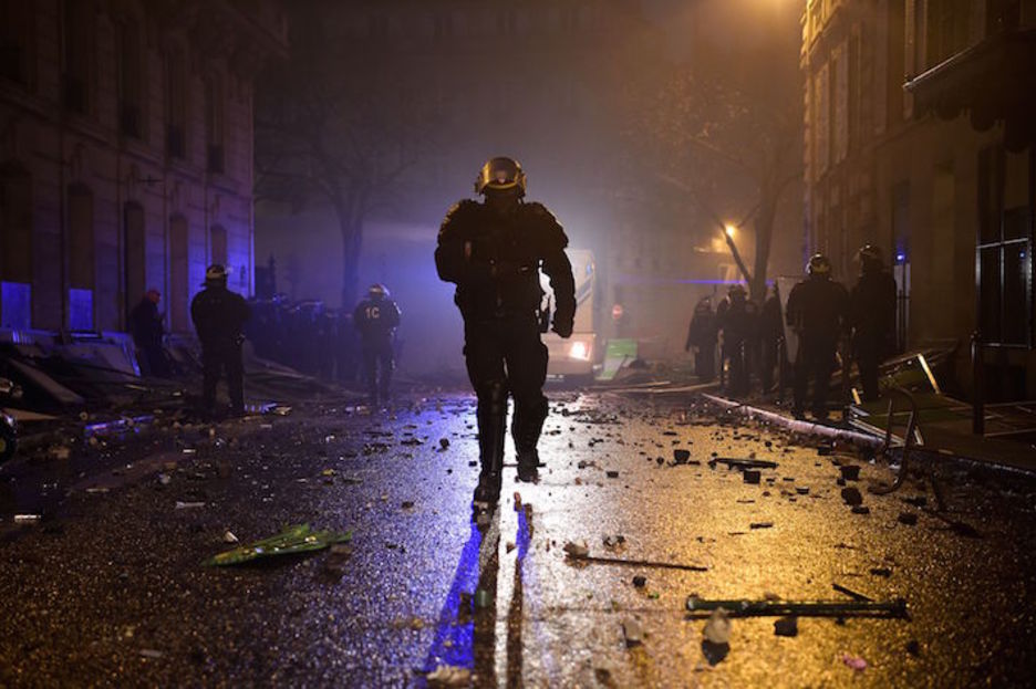 Polizia bat, Parisko erdiguneko kale batean barrena korrika. (Lucas BARIOULET/AFP) 