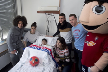 Los rojillos posan con uno de los niños ingresados. (Iñigo URIZ / FOKU)