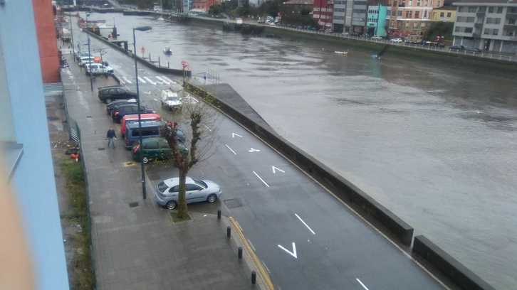 Carretera al lado de la ría que se ha desbordado con la pleamar.