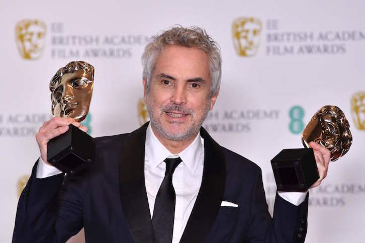 El cineasta mexicano Alfonso Cuarón posa con dos galardones. (Ben STANSALL/AFP)