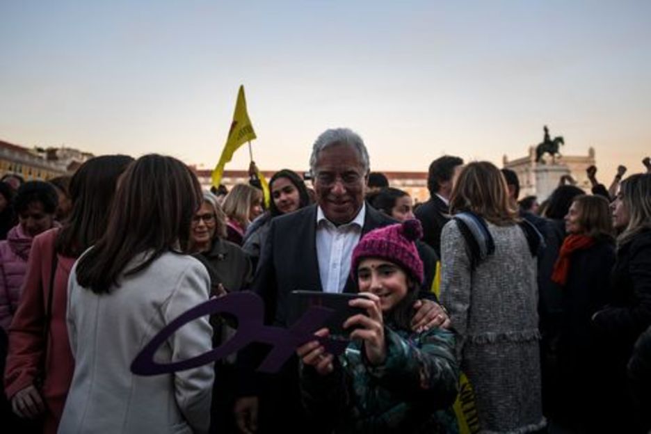 El primer ministro portugués Antonio Costa posa con una chica con el símbolo de la mujer. (PATRICIA DE MELO MOREIRA / AFP)