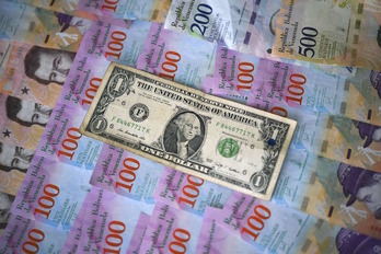 Un billete de un dólar junto a otros de bolívares venezolanos. (Yuri CORTEZ/AFP)