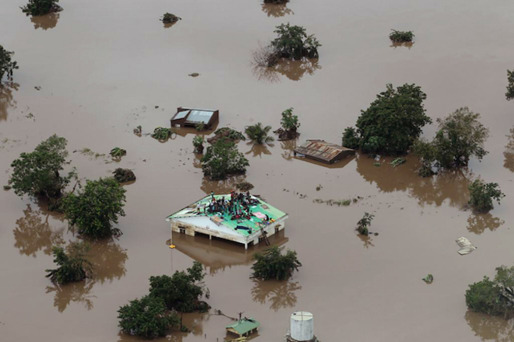 Un grupo de personas trata de mantenerse a salvo sobre un tejado en Beira, segunda ciudad más importante de Mozambique. (Rick EMENAKET/AFP)