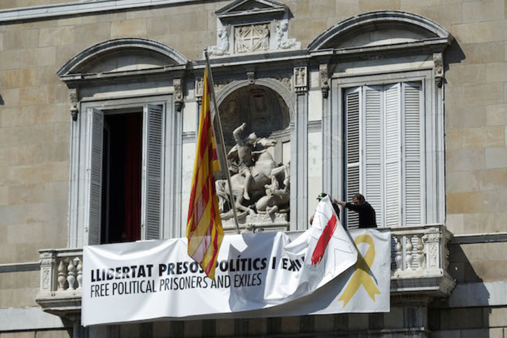 Operarios se disponen a retirar las dos pancartas del balcón de la Generalitat. (Pau BARRENA / AFP)