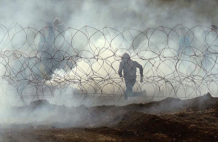 Un palestino corre junto a la valla de separación entre el humo de los gases en la protesta del sábado. (Jack GUEZ/AFP)