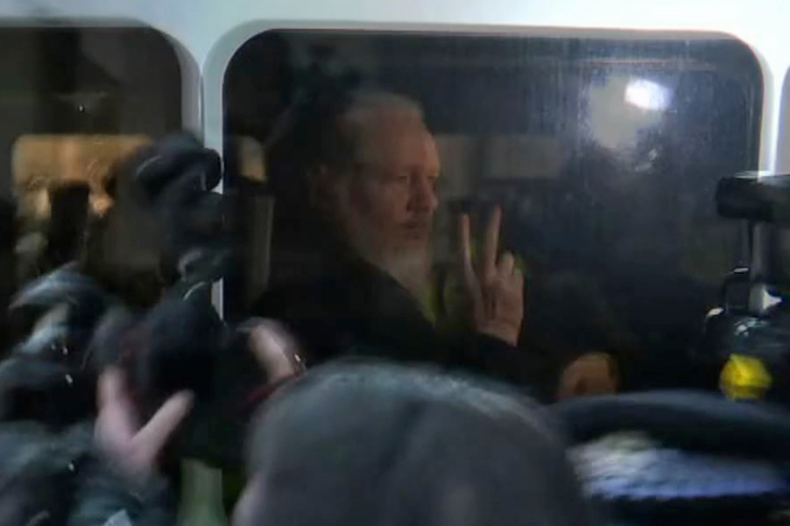 Julian Assange hace el signo de la victoria en el furgón policial, tras ser detenido. (AFP)