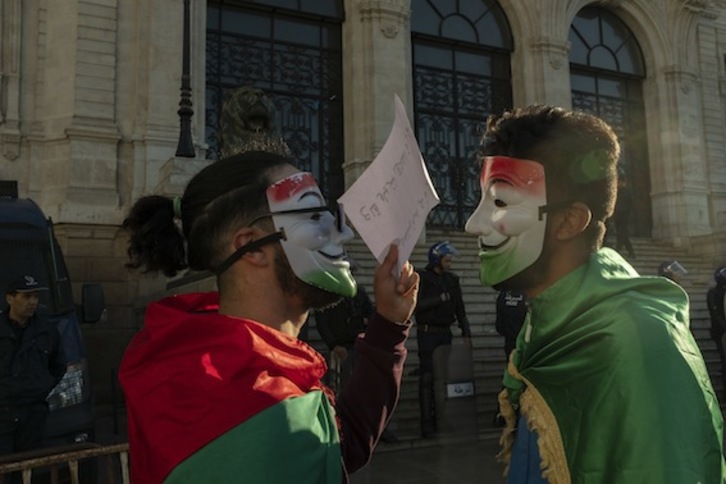 Dos jóvenes con la máscara de Anonymous, ante la Policía en las protestas de Orán. (Karim TOULIEB)