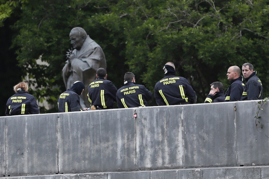 Bomberos se toman un respiro junto a la estatua de Juan Pablo II. (Zakaria ABDELKAFI / AFP) Bomberos se toman un respiro junto a la estatua de Juan Pablo II. (Zakaria ABDELKAFI / AFP)