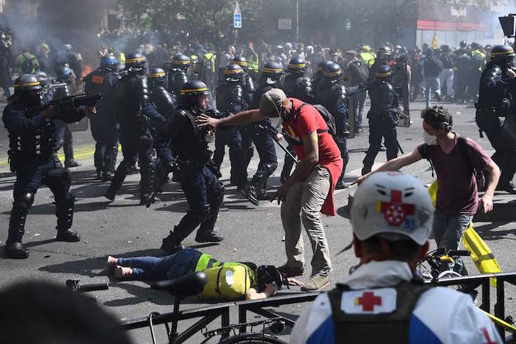 Un manifestante intenta ayudar a otro, caído en la carga policial. (Anne-Christine POUJOULA/AFP)T 