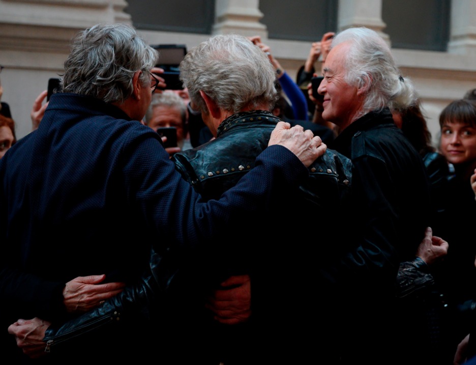 Los músicos Jimmy Page, Don Felder y Steve Miller se abrazan. (Don EMMERT / AFP)
