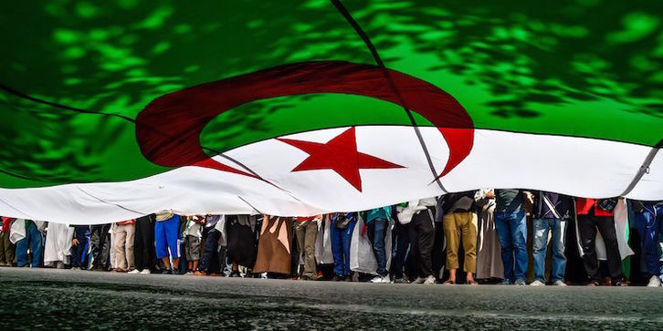 Manifestantes con una gran bandera argelina en las protestas del pasado viernes. (Ryad KRAMDI /AFP)