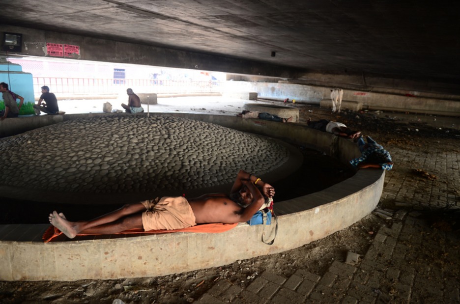 Un hombre descansa bajo la sombra de un puente. (Sanjay KANOJIA /AFP)