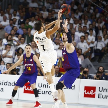 Un acrobático Campazzo suelta el balón frente a Tomic. El base argentino ha vuelto loco al Barça. (E. COBOS / ACB PHOTO)