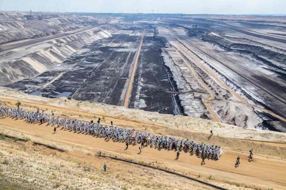 Decenas de activistas, con buzos blancos, pasan por uno de los caminos de la mina. (Marcel KUSCH/AFP)
