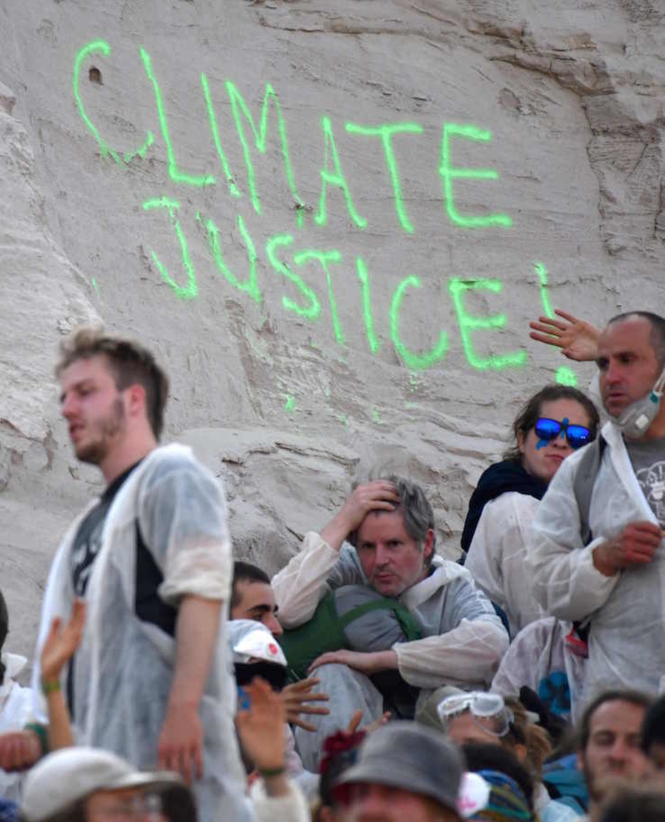 Activistas en la mina, junto a una pintada contra la crisis climática. (Ina FASSBENDER/AFP)