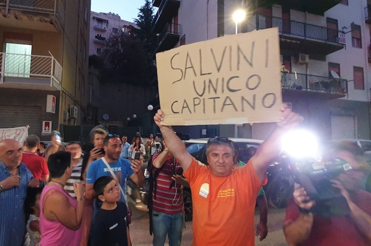 Un hombre muestra un cartel de apoyo a Salvini en el exterior del juzgado de Agrigento. (Giovanni ISOLINO / AFP)