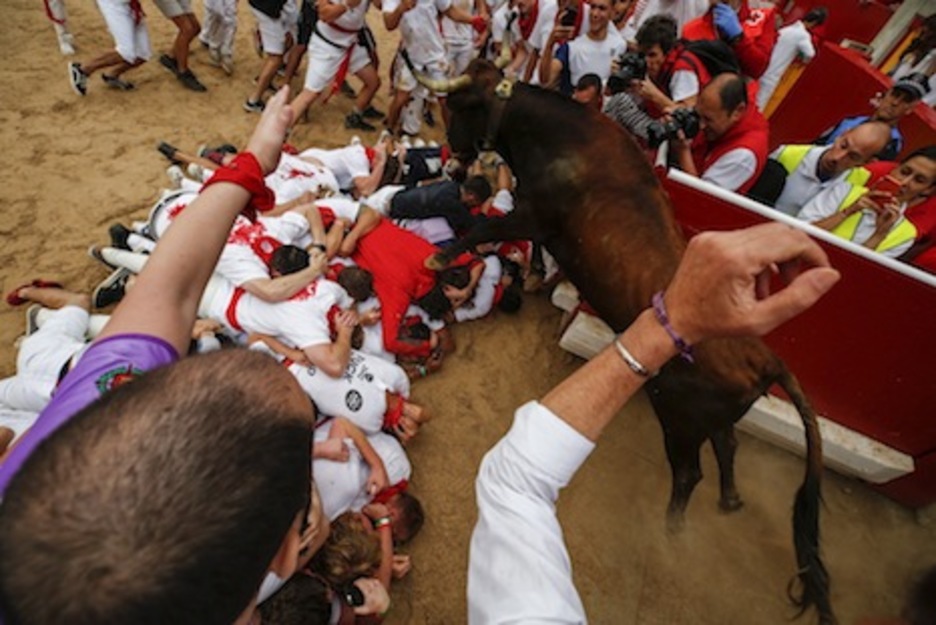 Otra vaca intenta salvar a los corredores tumbados en la arena. (Iñaki VERGARA/FOKU)