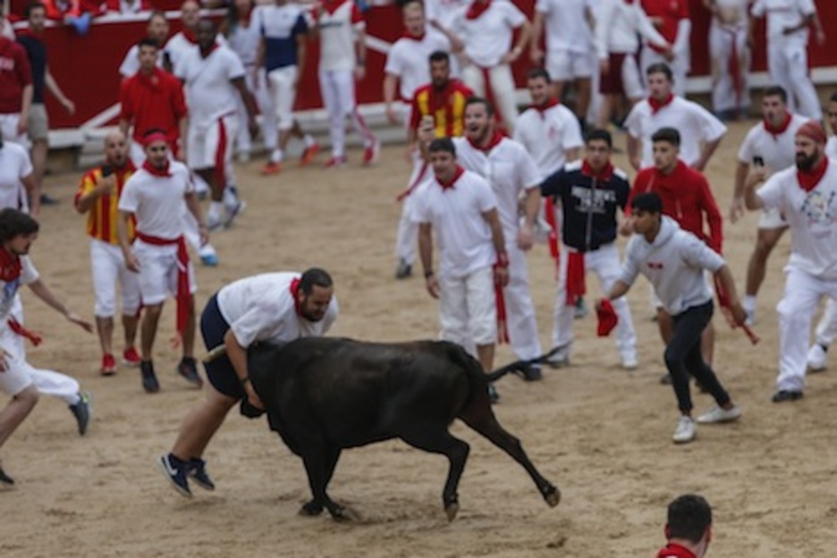 Un mozo intenta frenar a la vaca con su corpachón. (Iñaki VERGARA/FOKU)