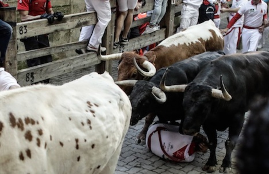 Dos toros de Jandilla pasan por encima de un mozo en el callejón, quien se protege como puede. (Joseba ZABALZA/FOKU) Dos toros de Jandilla pasan por encima de un mozo en el callejón, quien se protege como puede. (Joseba ZABALZA/FOKU)