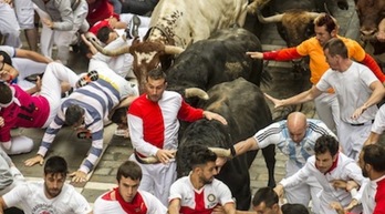Varios corredores tocan a los toros durante el encierro, un gesto que está prohibido. (FOKU)