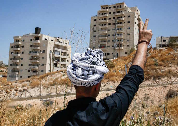 Un palestino hace el símbolo de la victoria ante algunos de los edificios amenazados.(Hazem BADER /AFP)