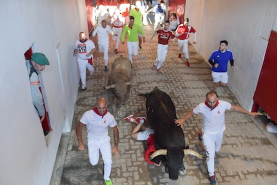 Un corredor se cubre como puede en el callejón ante la llegada de dos toros. (Idoia ZABALETA/FOKU)
