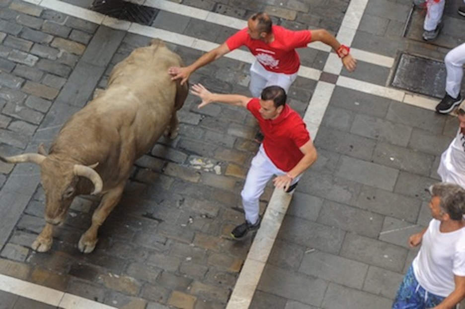 Dos mozos corren junto a Pregonero en la Estafeta. (Lander ARROYABE/FOKU)