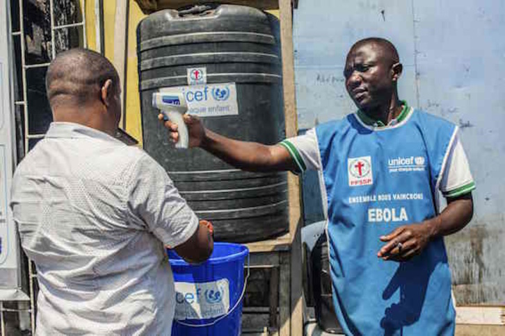 Un trabajador de Unicef toma la temperatura y dispensa agua a la ciudadanía de Goma. (Pamela TULIZO/AFP)