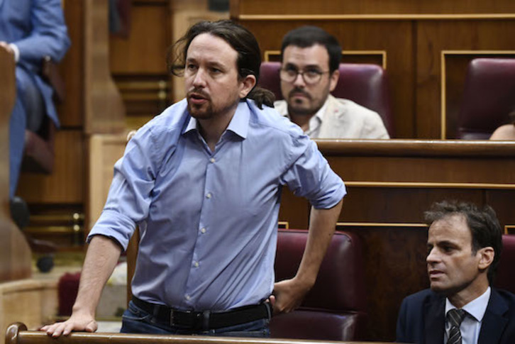 Alberto Garzón, de IU, sentado detrás de Pablo Iglesias. (Óscar DEL POZO/AFP)