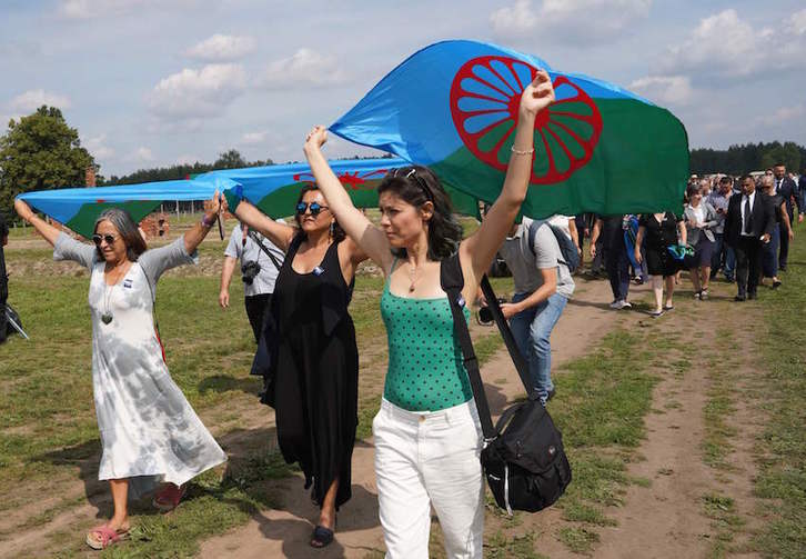 Mujeres ondean banderas romaníes para conmemorar el 75 aniversario del Samudaripen en los terrenos de Auschwitz-Birkenau. (Alik KEPLICZ/AFP)