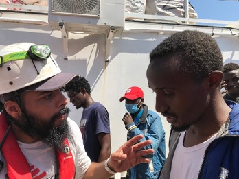 Un voluntario y un migrante, en la cubierta del Ocean Viking, también en apuros. (Anne CHAON | AFP)