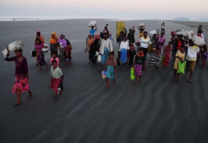 Refugiados rohingya caminan sobre la playa de Saplapur tras huir a Bangladesh por mar en noviembre de 2017. (Dibyangshu SARKAR/AFP)