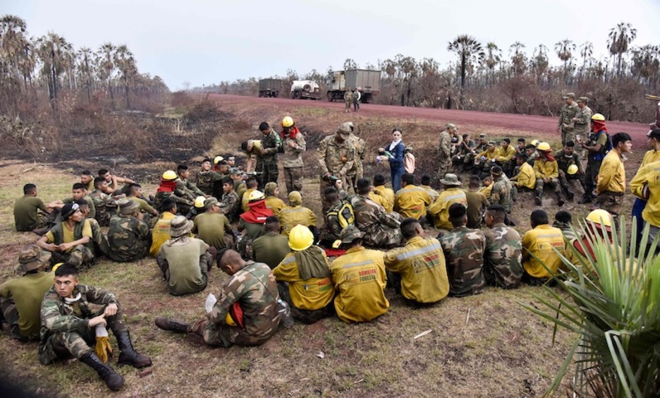Una brigada descansa en una zona semiquemada. (Aizar RALDES | AFP)