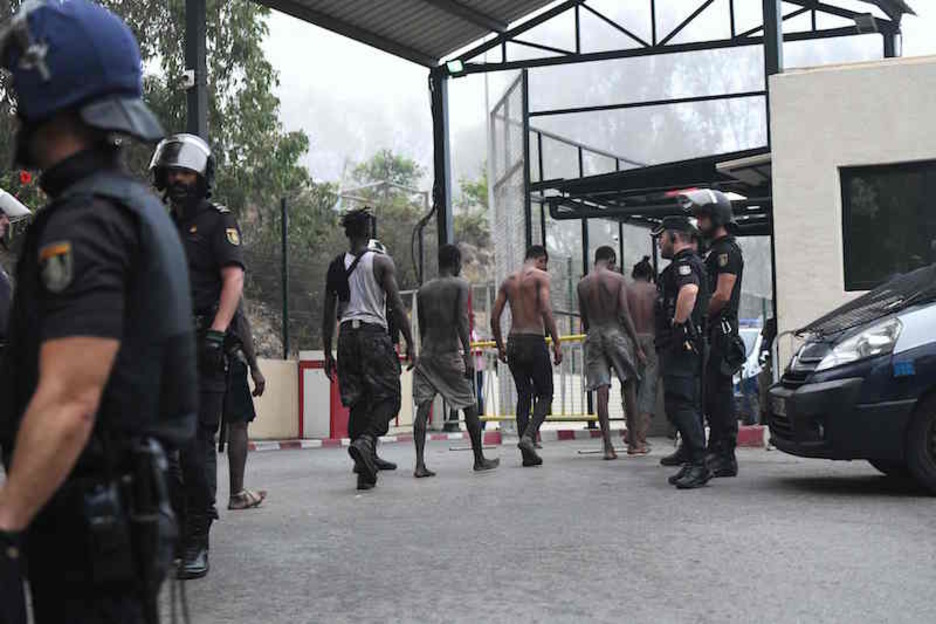 Los migrantes son detenidos tras haber logrado saltar la valla de Ceuta. (Antonio SEMPERE/AFP)