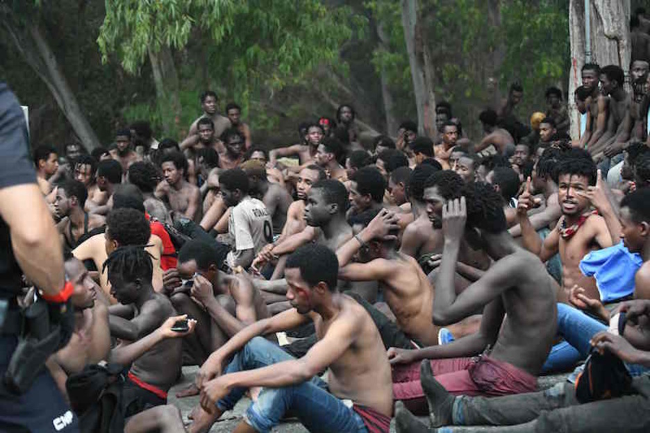 Detención de los migrantes tras pasar la valla de Ceuta. (Antonio SEMPERE/AFP)