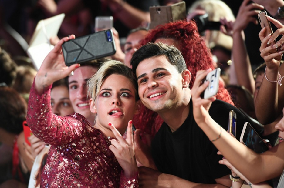 La actriz estadounidense Kristen Stewart posa para un selfie con un fan. (Vincenzo PINTO / AFP)