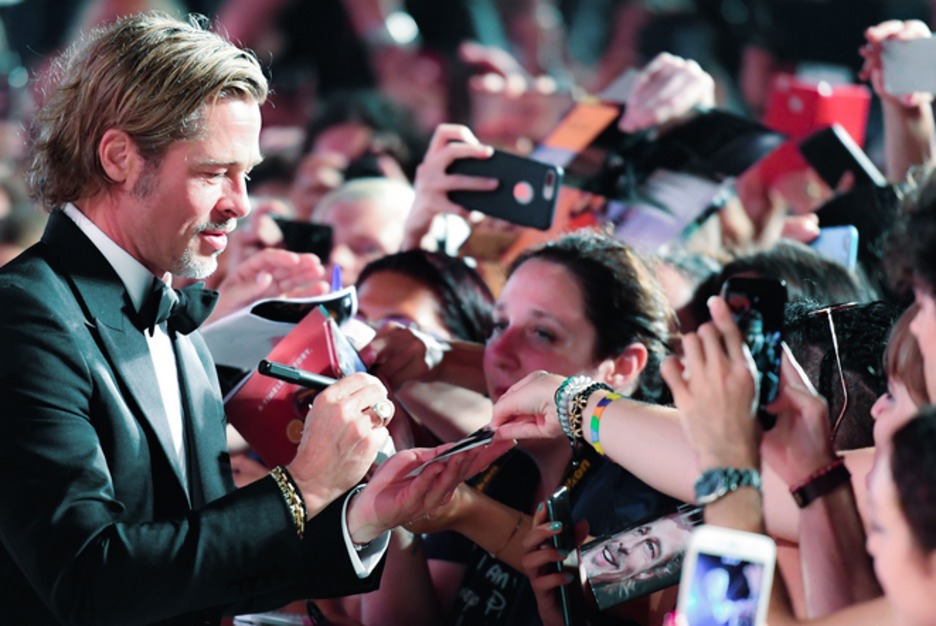 El actor Brad Pitt firma autografos a sus fans. (Alberto PIZZOLI / AFP)