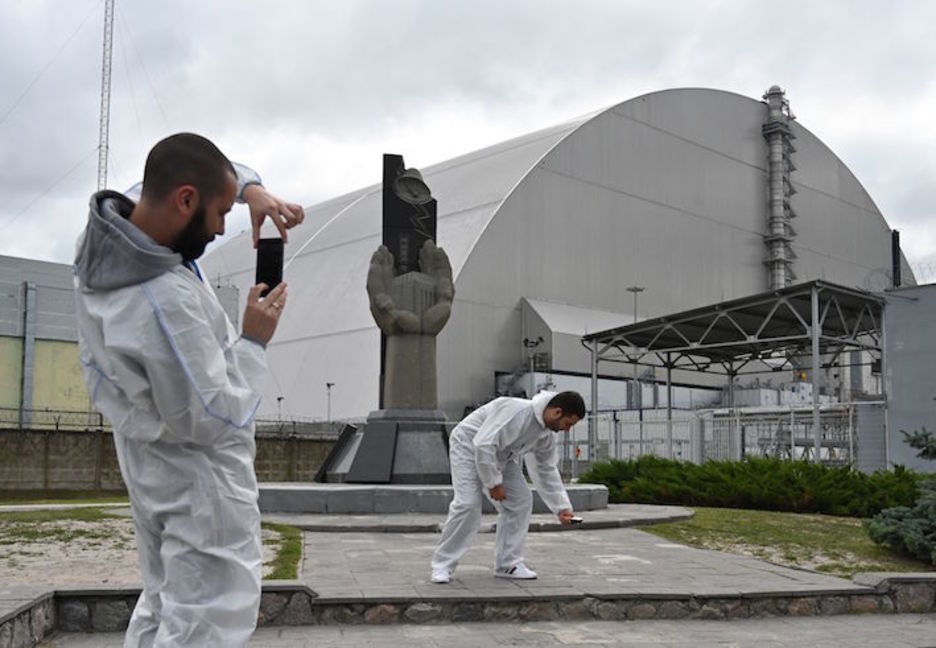 Turistas se fotografían junto al sarcófago que encierra el reactor destruido. (Genya SAVILOV/AFP)
